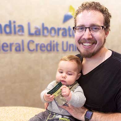Ryan and Lincoln McCoy in front of Sandia Laboratory Federal Credit Union Logo